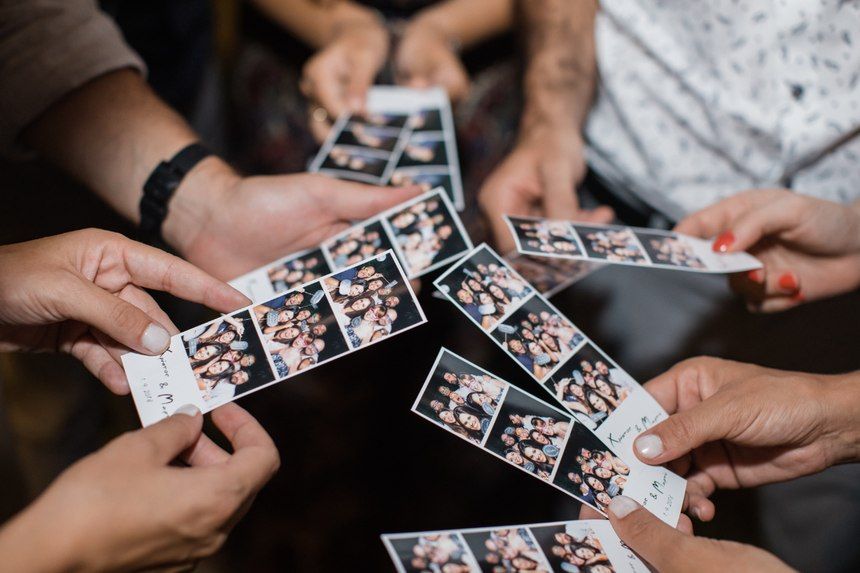 Hands holding photo strips during a gathering spread out on a dark surface.