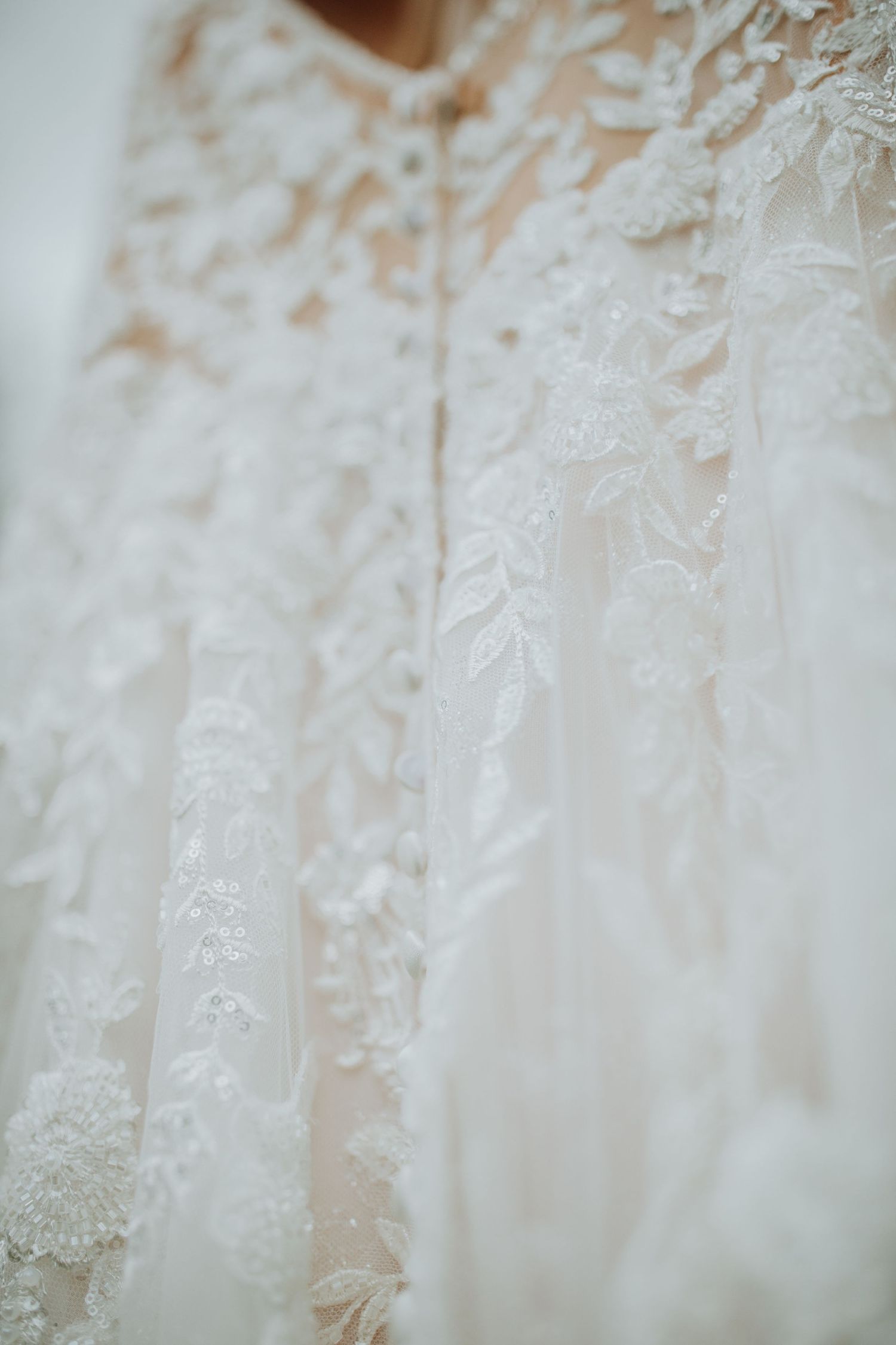 Close-up detail of intricate lace patterns on a white wedding dress.