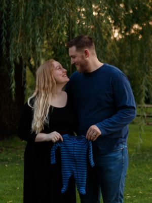couple holding a baby onsie