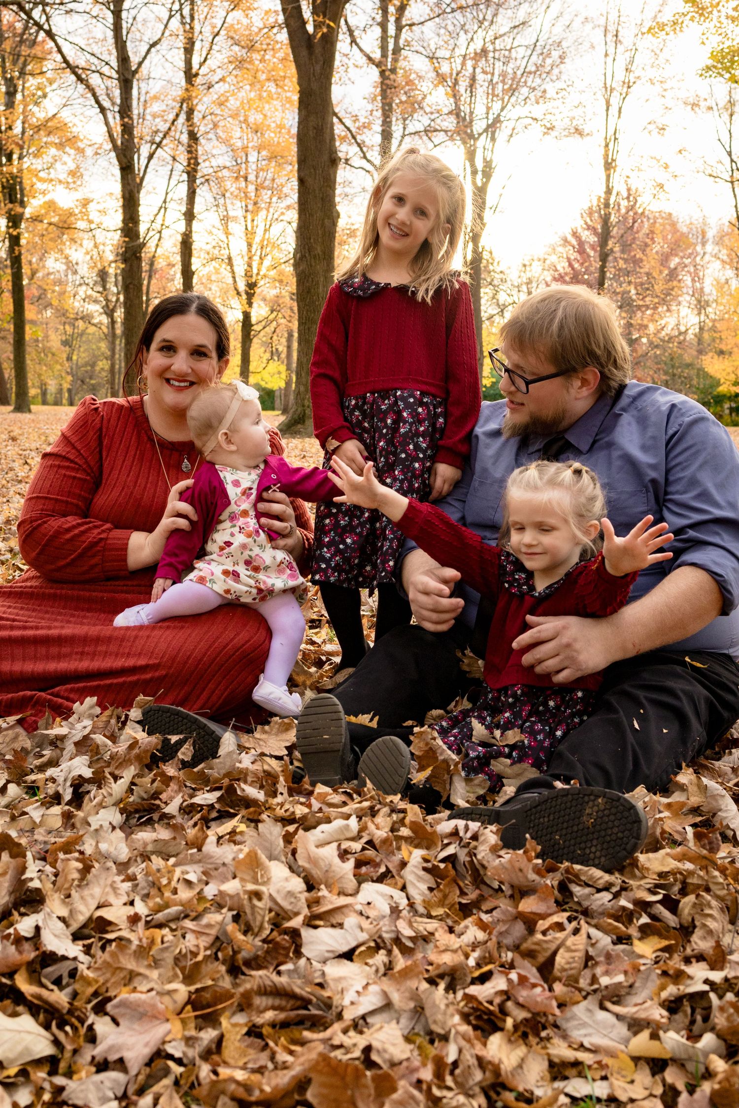 Family enjoying playful moments together in a bed of autumn leaves.
