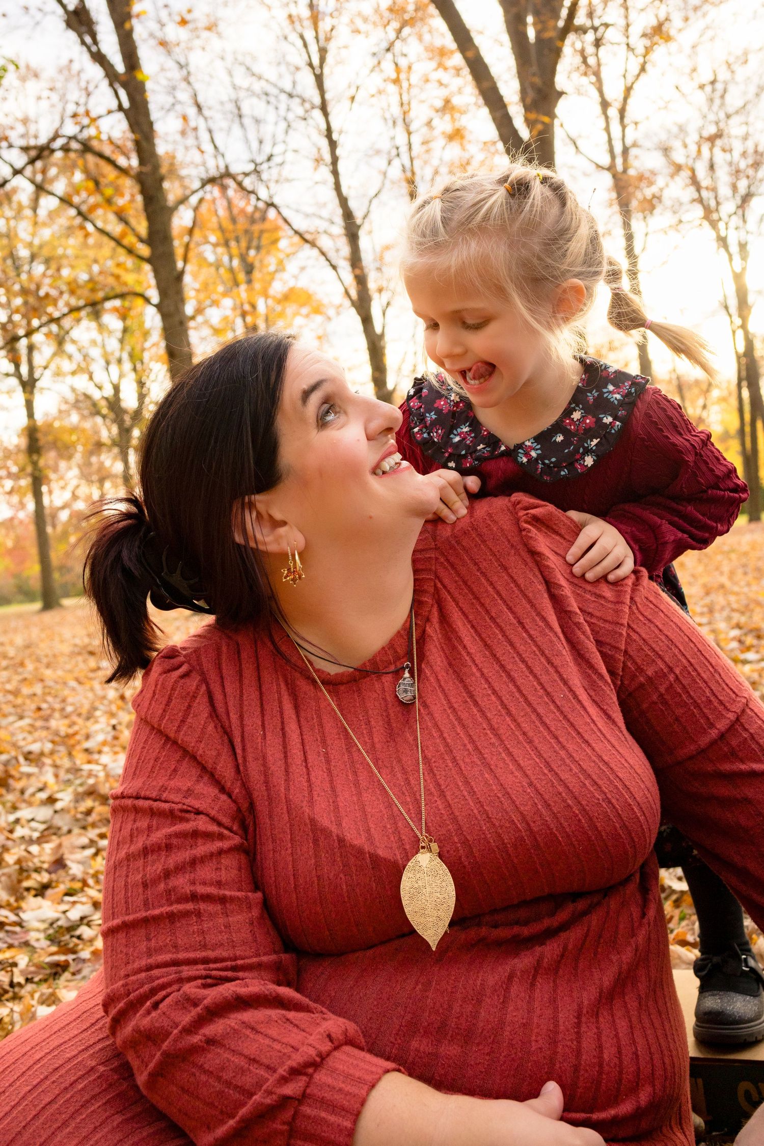 Two people share a joyful moment while sitting among fallen autumn leaves.