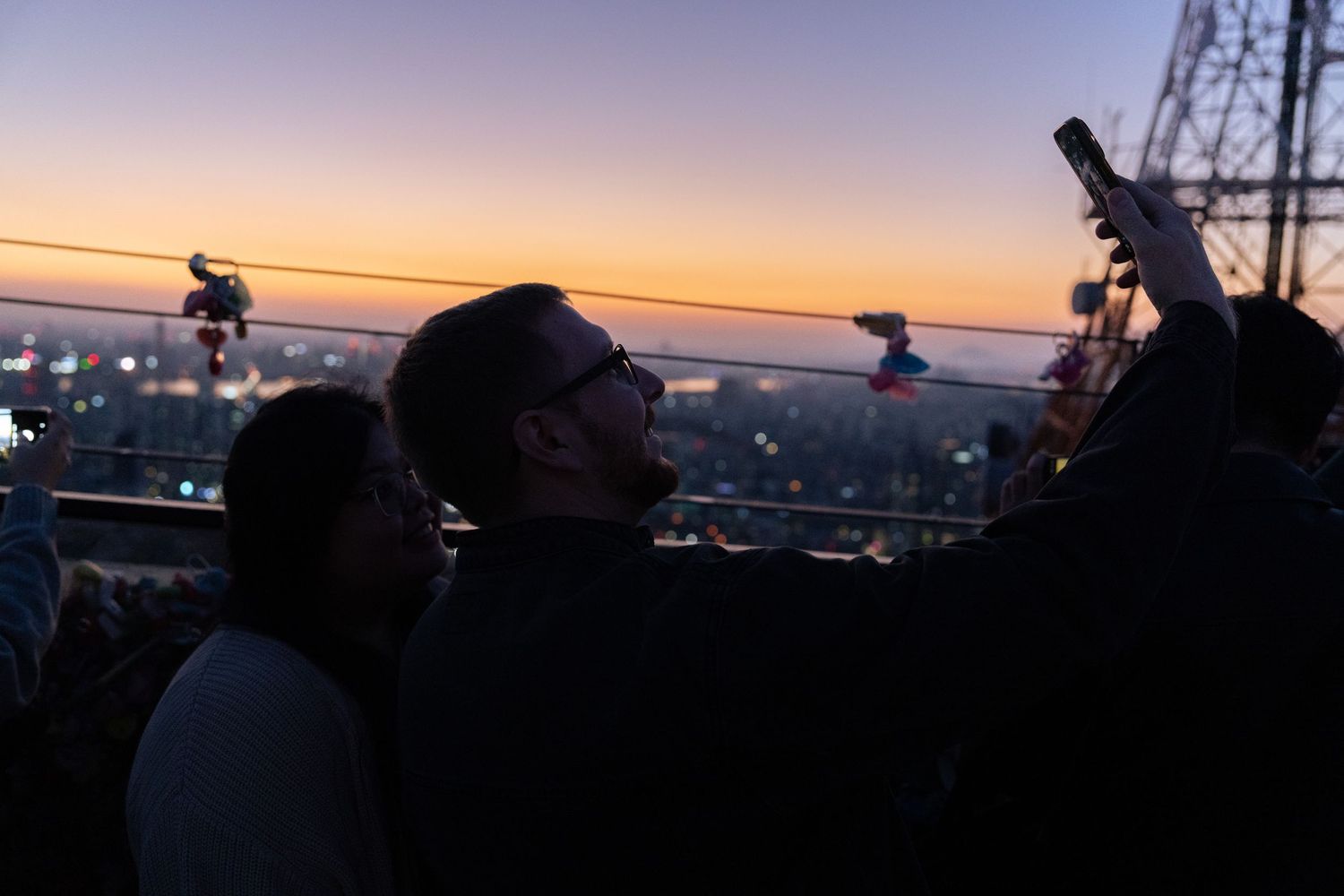 Silhouettes of people photographing a cityscape at sunset.