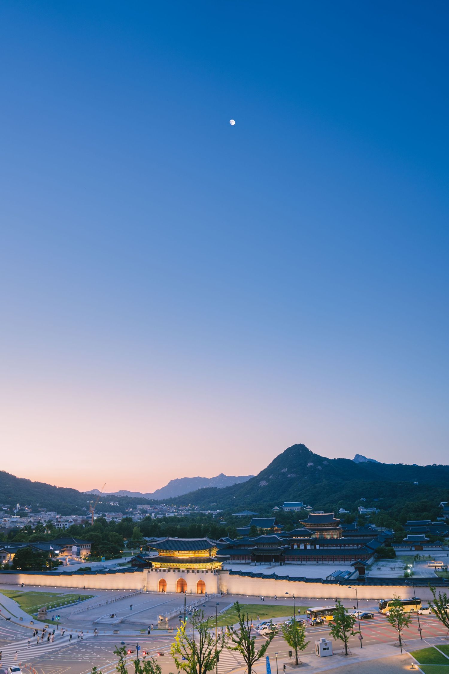 Panoramic sunset view of Gyeongbokgung Palace and mountains in Seoul.