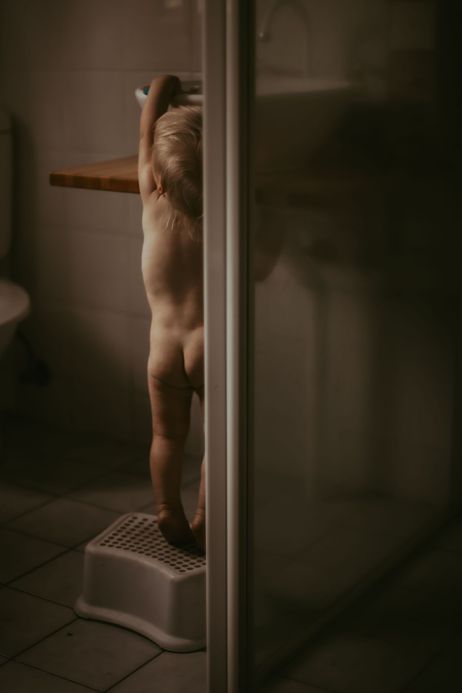 Toddler standing on a bath step to reach the sink