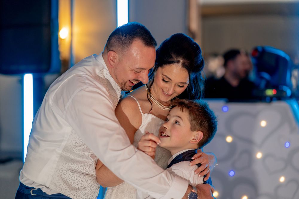 A tender family embrace moment during a celebration with blue lighting in the background.