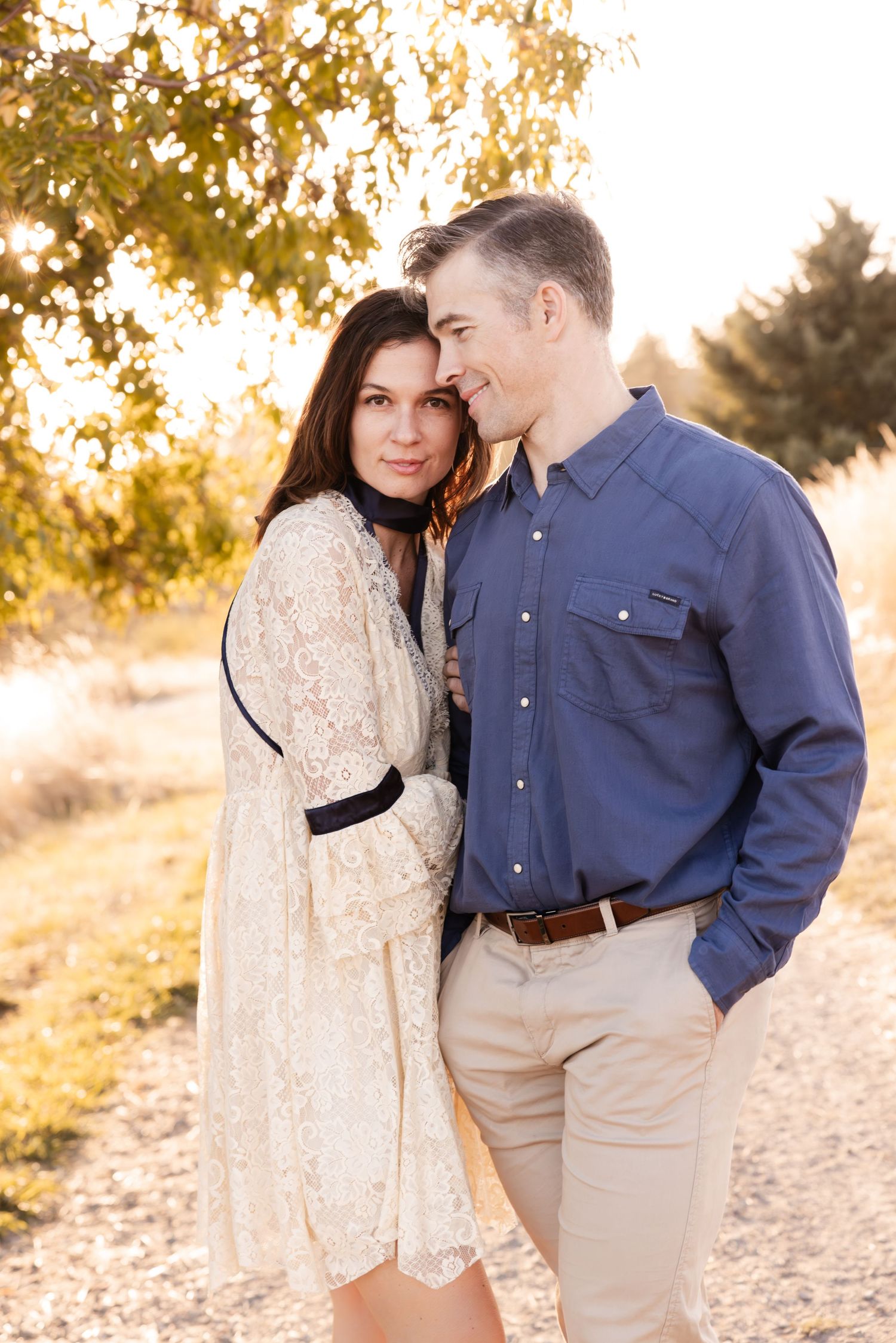 Couple in coordinated outfits sharing an intimate moment on a path with trees in background.
