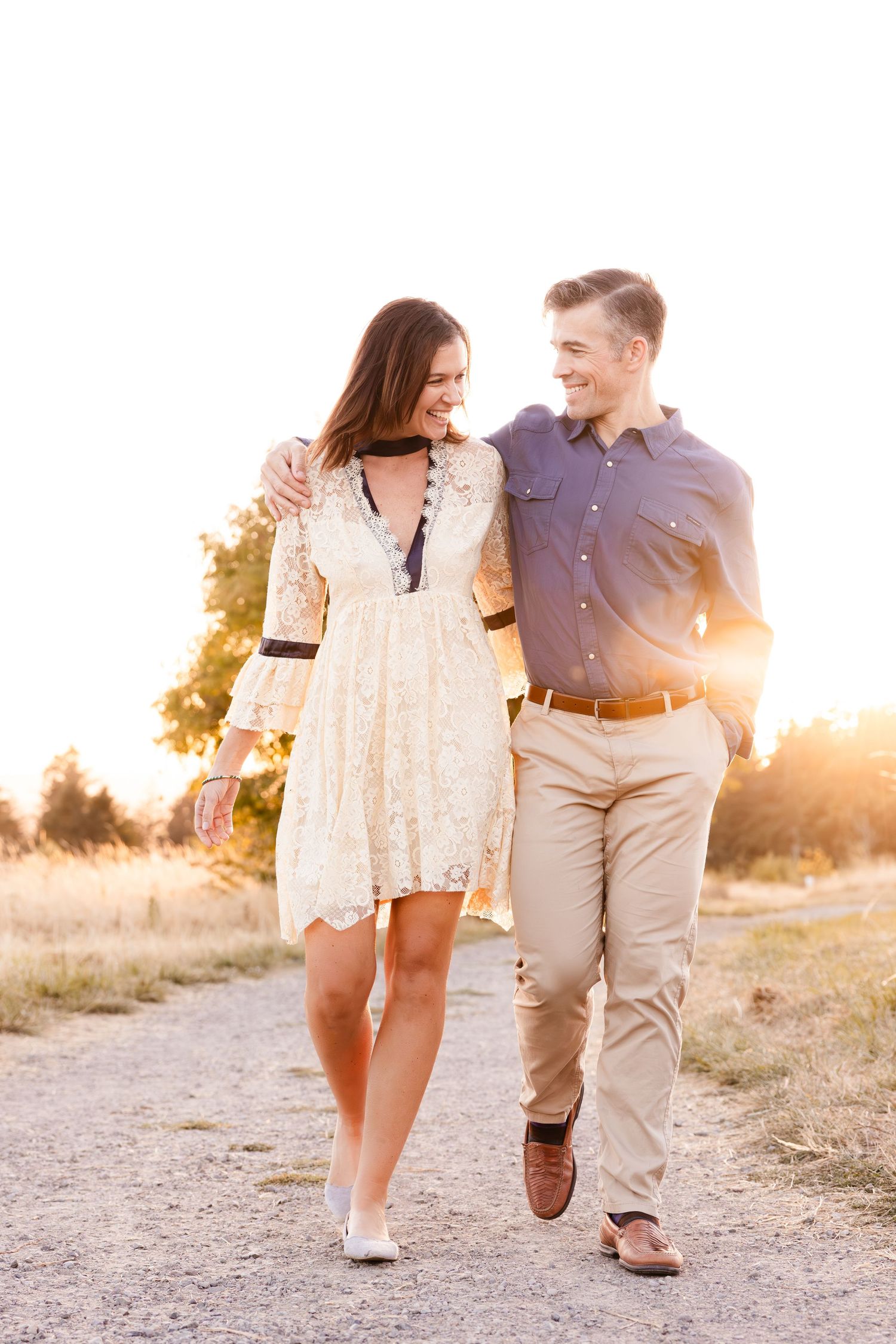 Couple walking together on a path during golden hour wearing coordinated outfits.