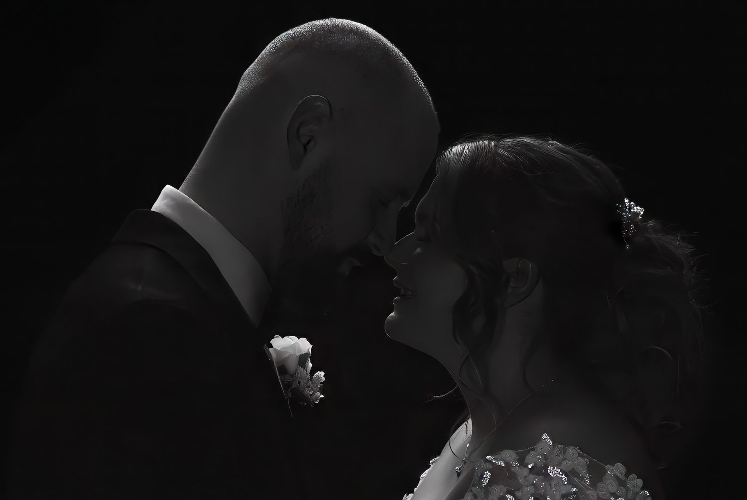 An intimate black and white wedding portrait with dramatic shadows and lighting.