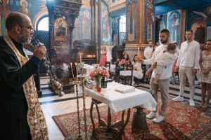 Orthodox priest conducting religious ceremony with incense in decorated church interior.