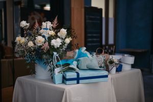 Elegant table setting with white and blue floral centerpiece and wrapped gifts.