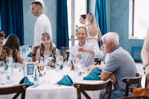 Guests enjoying a formal dining celebration at round tables with blue decor.