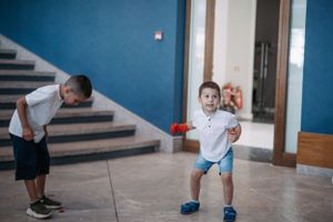 A playful scene of a child running while someone bends down in a blue hallway.