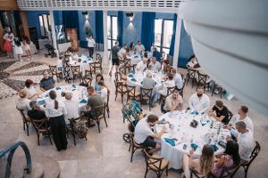 Aerial view of wedding reception with guests seated at round tables in blue-themed venue.
