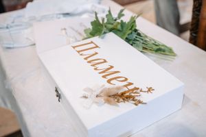 White baptism invitation box with green floral decoration.