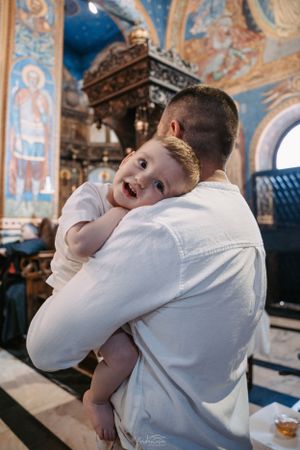 Child hugging their parent inside a beautifully decorated orthodox church.