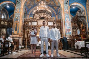 Group standing in front of iconostasis in Orthodox church with blue and gold murals.