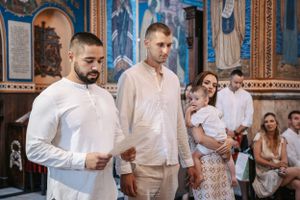 People participating in Orthodox church ceremony wearing white and cream colored attire.