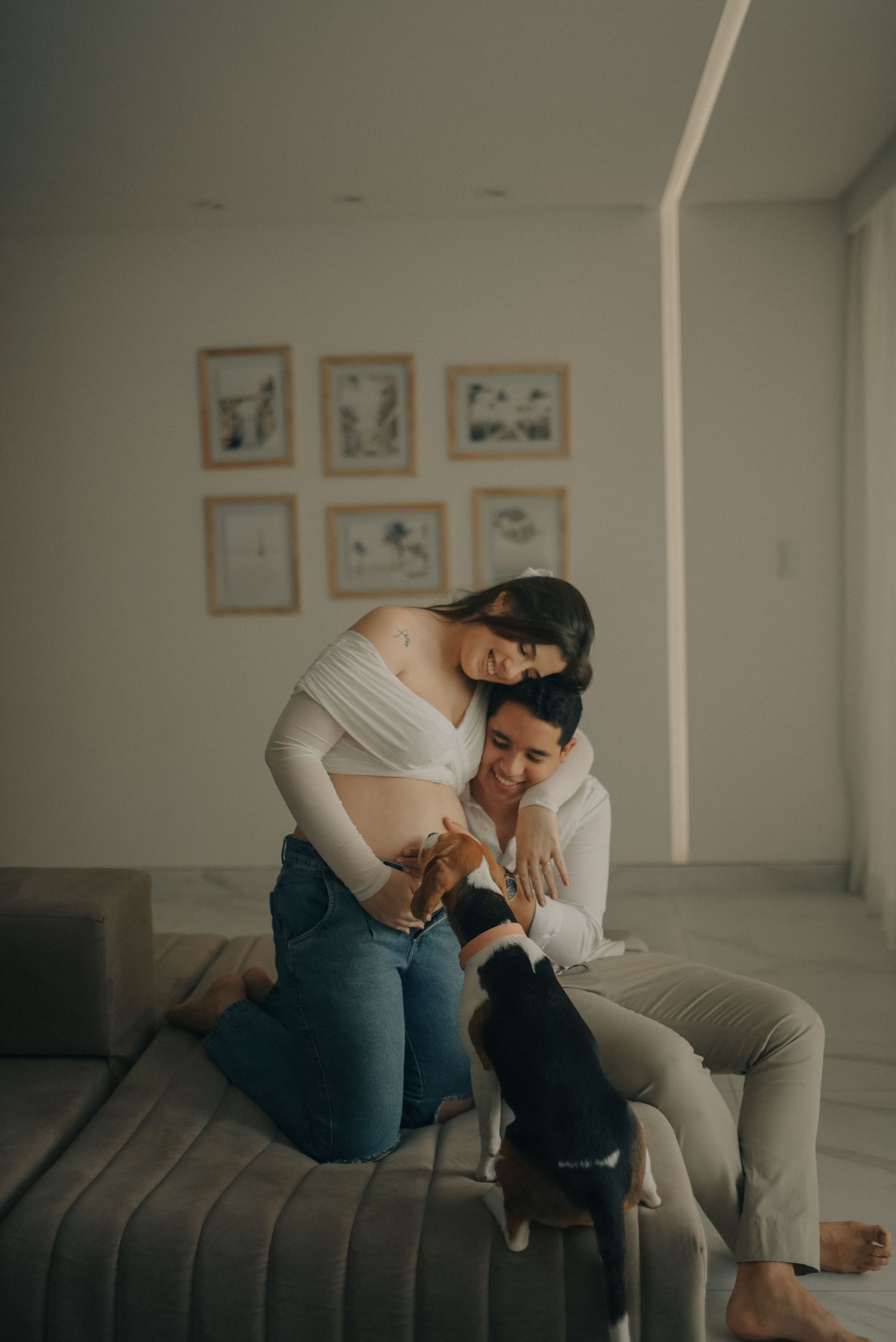 Couple relaxing on couch with dog in modern living room with framed art.