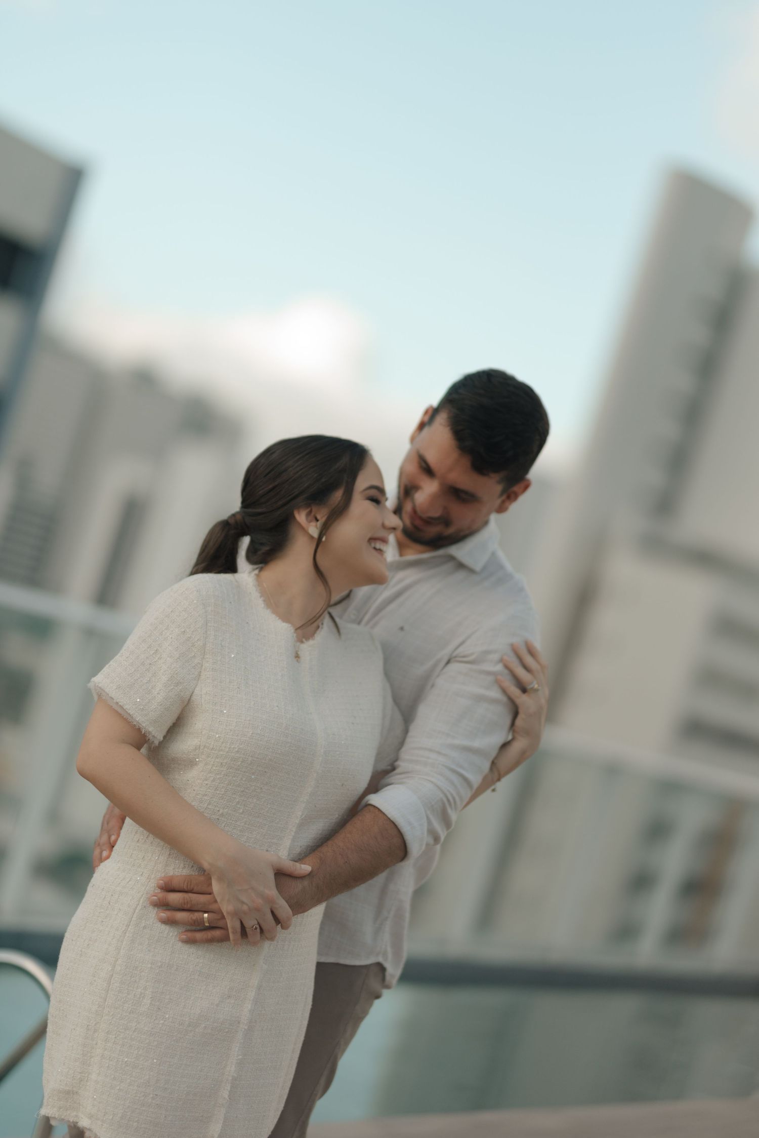 Couple sharing intimate moment on urban rooftop with city skyline backdrop.
