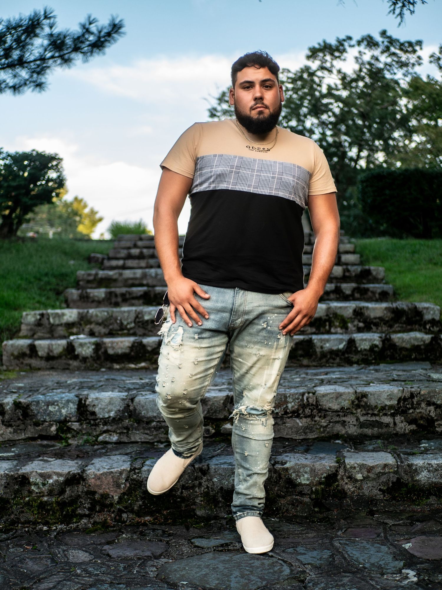 Fashion photography on outdoor stone stairs showing casual streetwear styling against a natural backdrop.