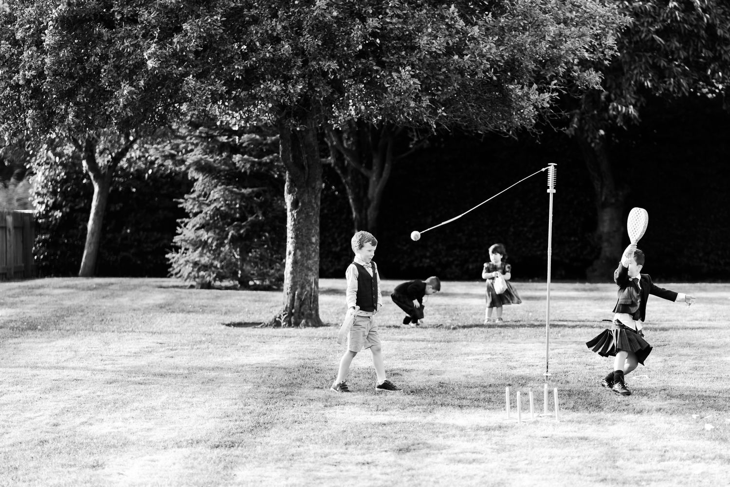 Vintage black and white photograph of children playing tetherball in a park setting.