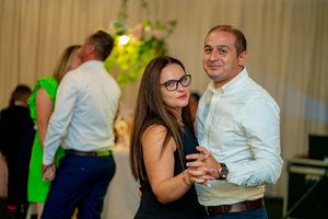 Couples enjoying social dancing at an indoor event venue with mood lighting.