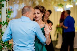 Couples dancing together at a wedding reception with green decor and ambient lighting.