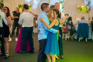 Wedding celebration with newlyweds posing against a floral backdrop with pink lighting.