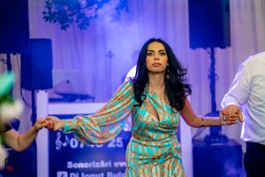 Dancer in turquoise outfit performing expressive moves under blue stage lighting.