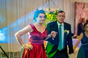 Dancers in formal attire performing at an indoor celebration with decorative lighting.