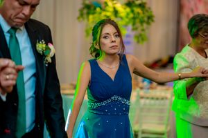 Woman in sparkly blue formal dress dancing at an elegantly decorated event venue.