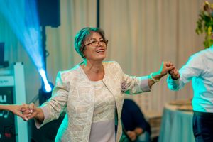 Woman in white lace dress dancing joyfully at a celebration with blue lighting effects.