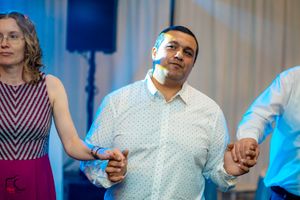 People holding hands while dancing in a line at an indoor celebration.