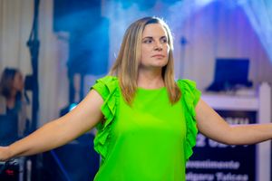 Woman in bright neon green ruffled dress dancing with arms outstretched.