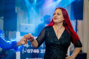 Woman in a sparkly black dress dancing under blue stage lighting.