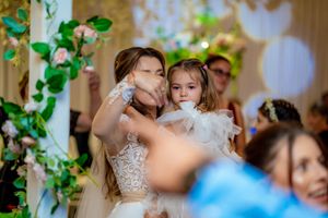 Dancing and celebration at a wedding reception with decorative greenery and warm lighting.