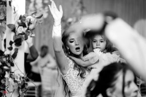 Black and white photo of joyful dancing at a wedding reception with decorative vines.