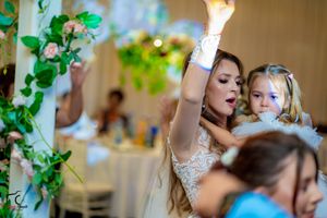 Wedding celebration with guests dancing and enjoying festivities under decorative green vines.