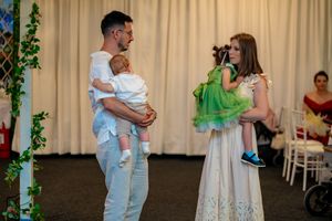 Parents hold their baby while speaking at a wedding reception.