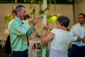 Two wedding guests dance and laugh together at a reception.