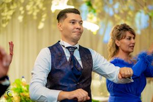 Dancers in formal attire perform at a wedding reception with decorative lighting.