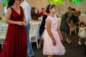 Wedding reception guests in formal attire standing near elegant white tables.