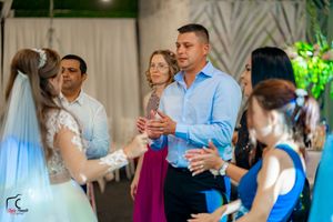 Wedding guests dancing and mingling at an indoor reception with decorative greenery.