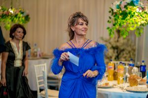Celebration attendees interacting at a formal event with floral and greenery decorations.