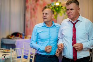 Formal event attendees in suits and ties engaging in conversation at an indoor venue.