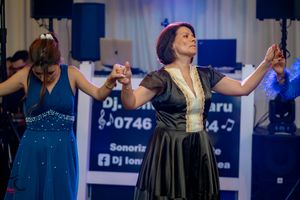 Formal dance party with dramatic blue stage lighting and white backdrop.