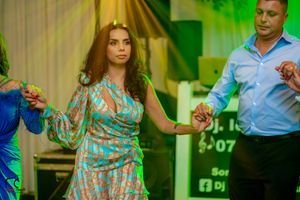 Couples dancing together at a formal event with dramatic green stage lighting.