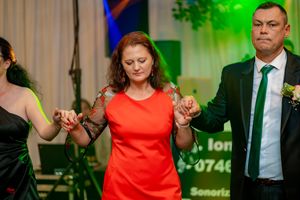 Couples dancing together at a formal event with dramatic green and blue lighting.