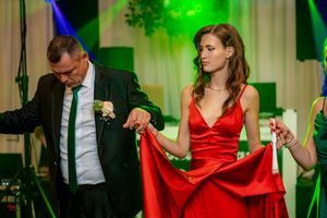Dance partners performing elegant moves at a formal event with green lighting effects.