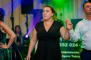 People dancing at a formal event with dramatic blue and green stage lighting.